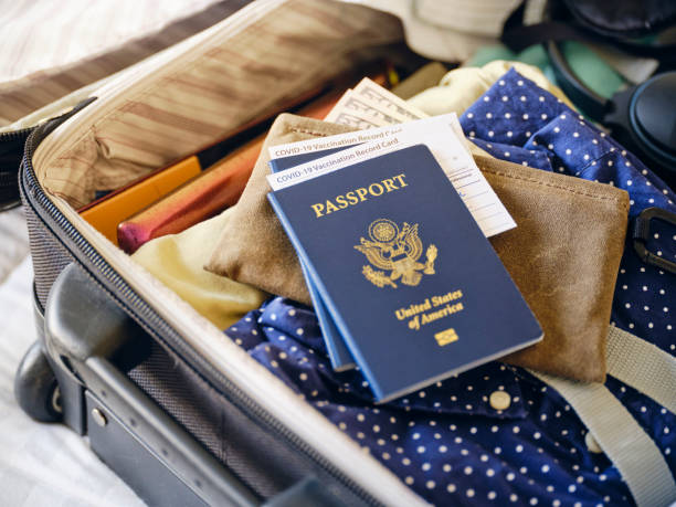 A suitcase COVID vaccination card, and passport being prepared for a trip.